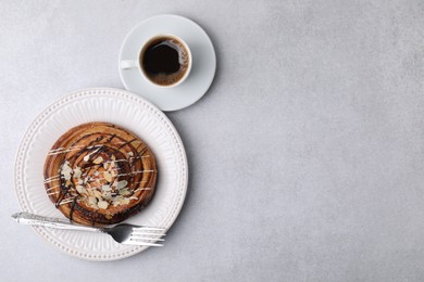 Photo of Delicious roll with poppy seeds, coffee and fork served on light grey table, flat lay with space for text. Sweet bun