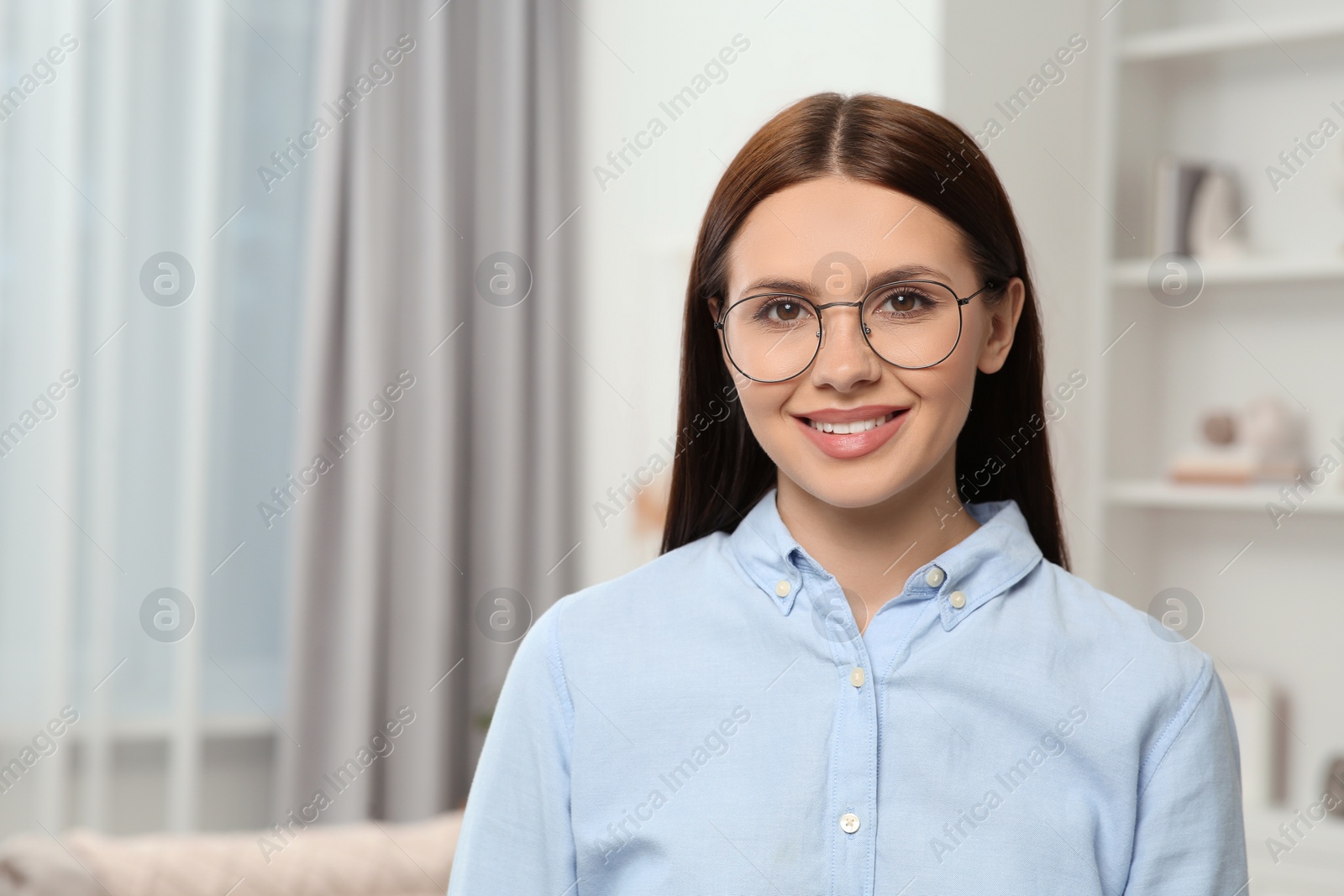 Photo of Portrait of smiling woman in stylish eyeglasses at home. Space for text
