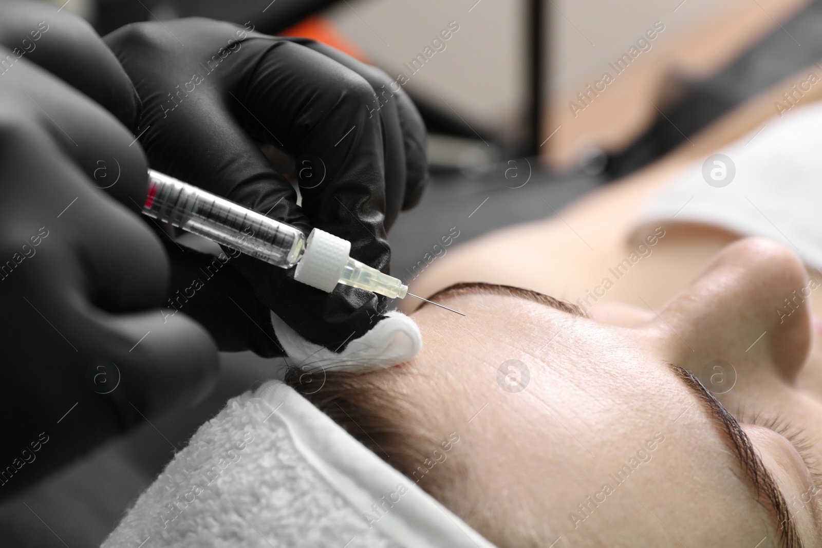 Photo of Cosmetologist giving facial injection to patient in clinic, closeup. Cosmetic surgery