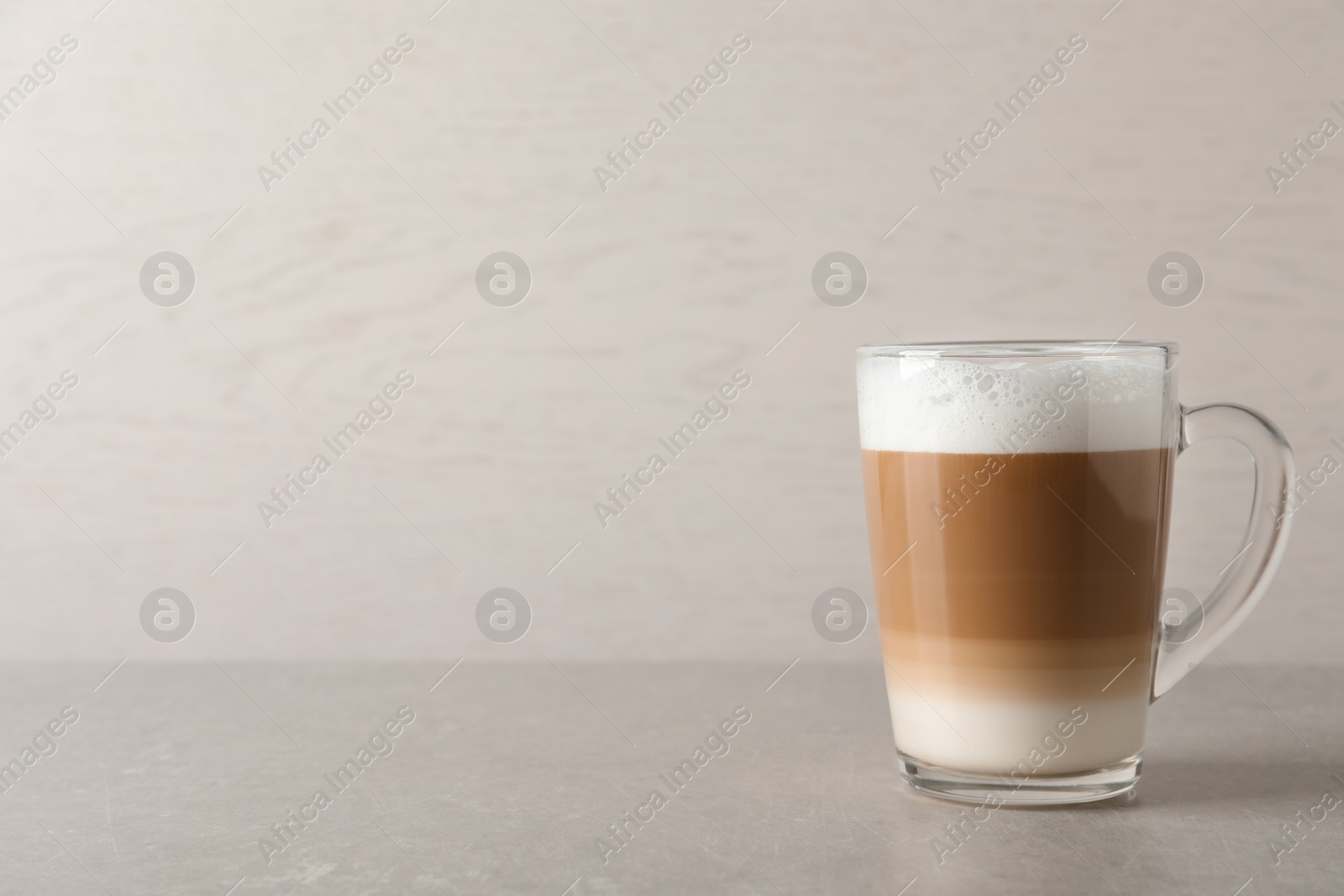 Photo of Hot coffee with milk in glass cup on light table. Space for text