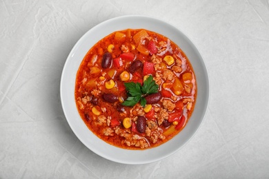 Plate with tasty chili con carne on gray background, top view