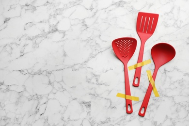 Photo of Different clean kitchen utensils on marble background, flat lay. Space for text