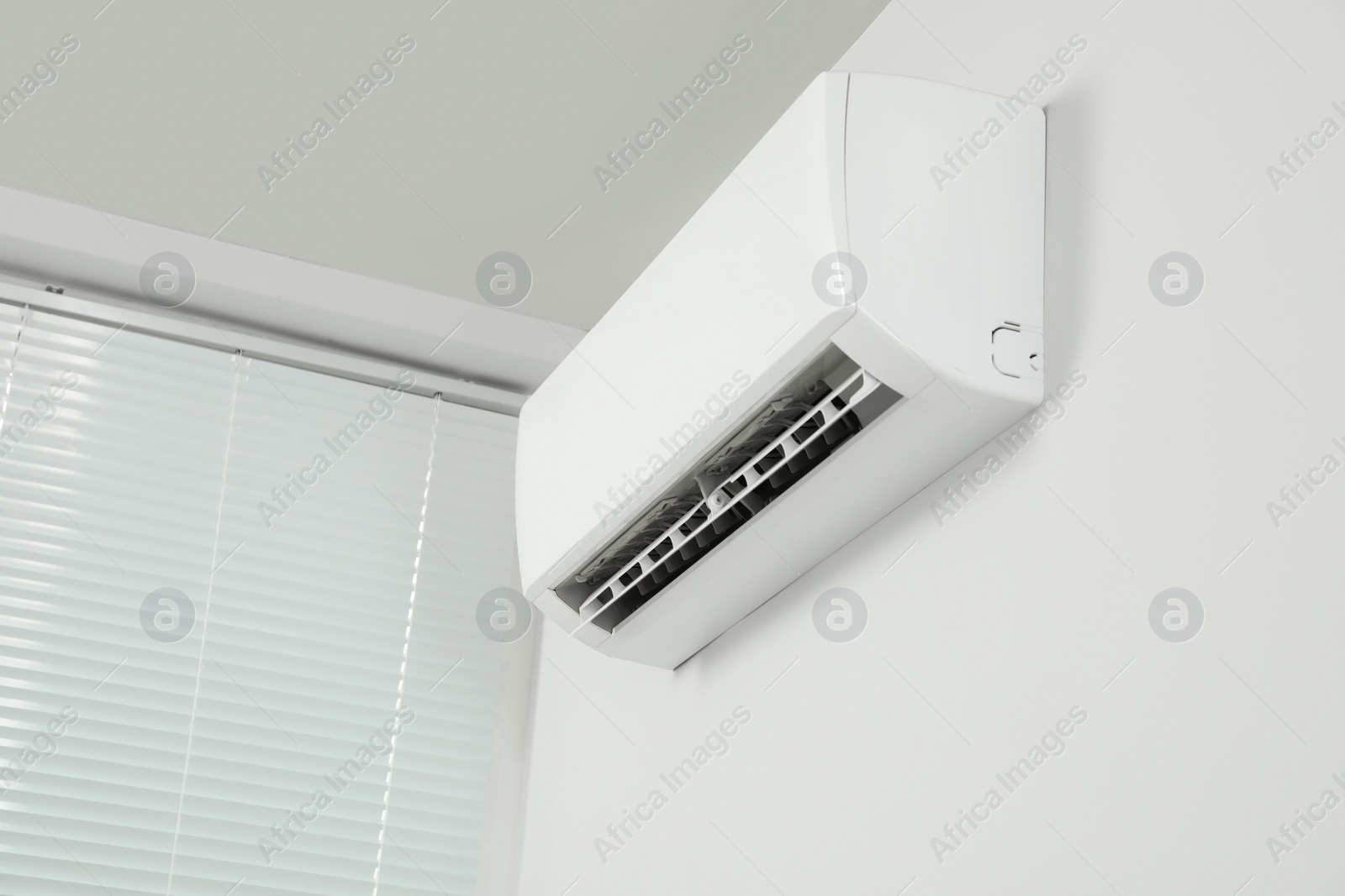 Photo of Modern air conditioner on white wall indoors, low angle view