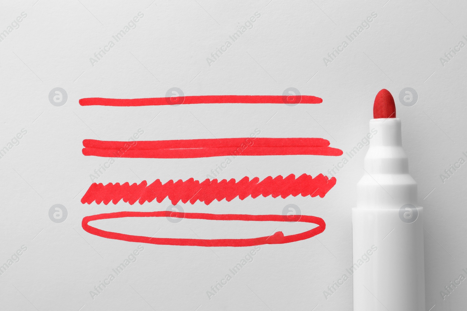 Photo of Different stripes and ellipse drawn with red marker isolated on white, top view