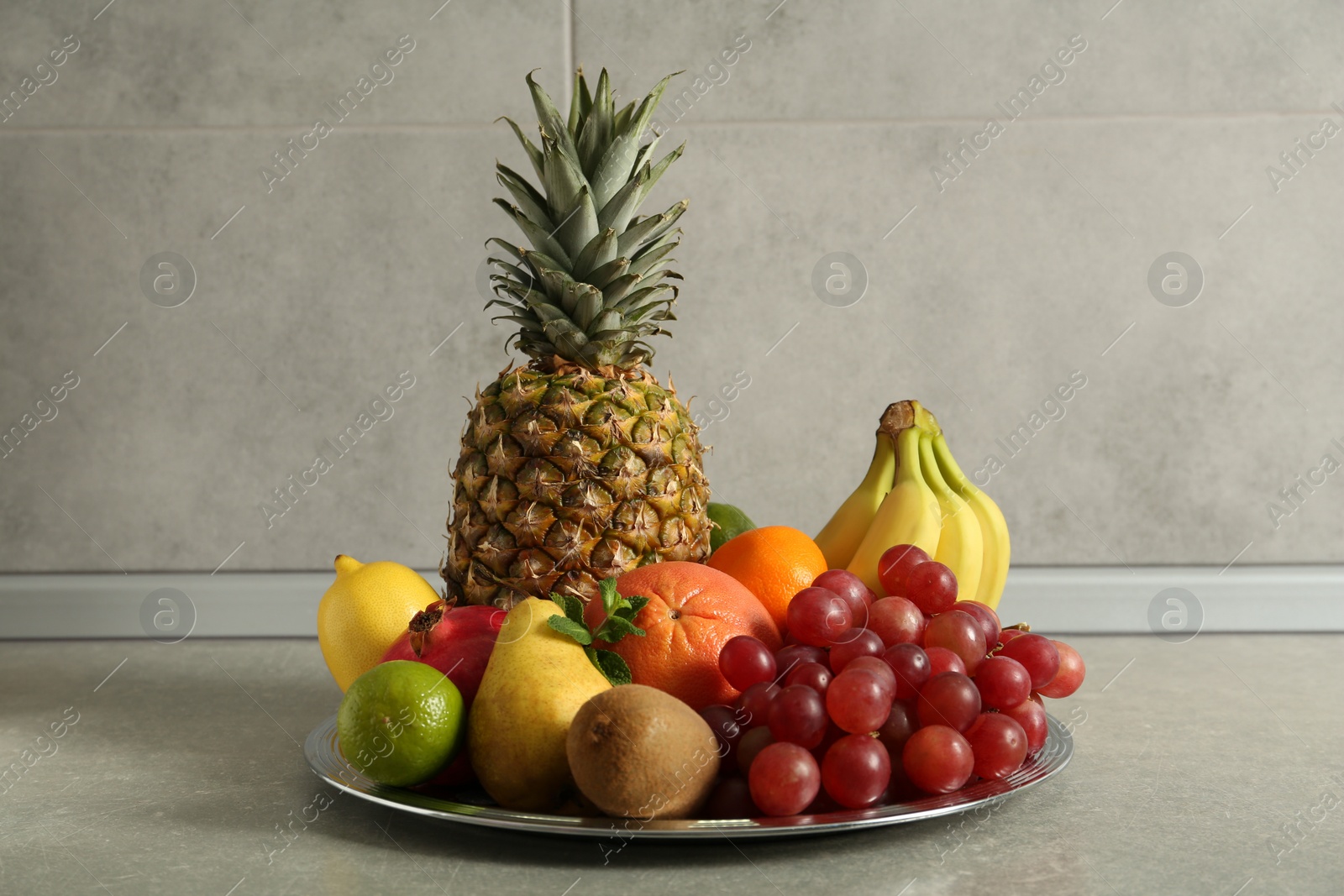 Photo of Plate with different ripe fruits on grey table