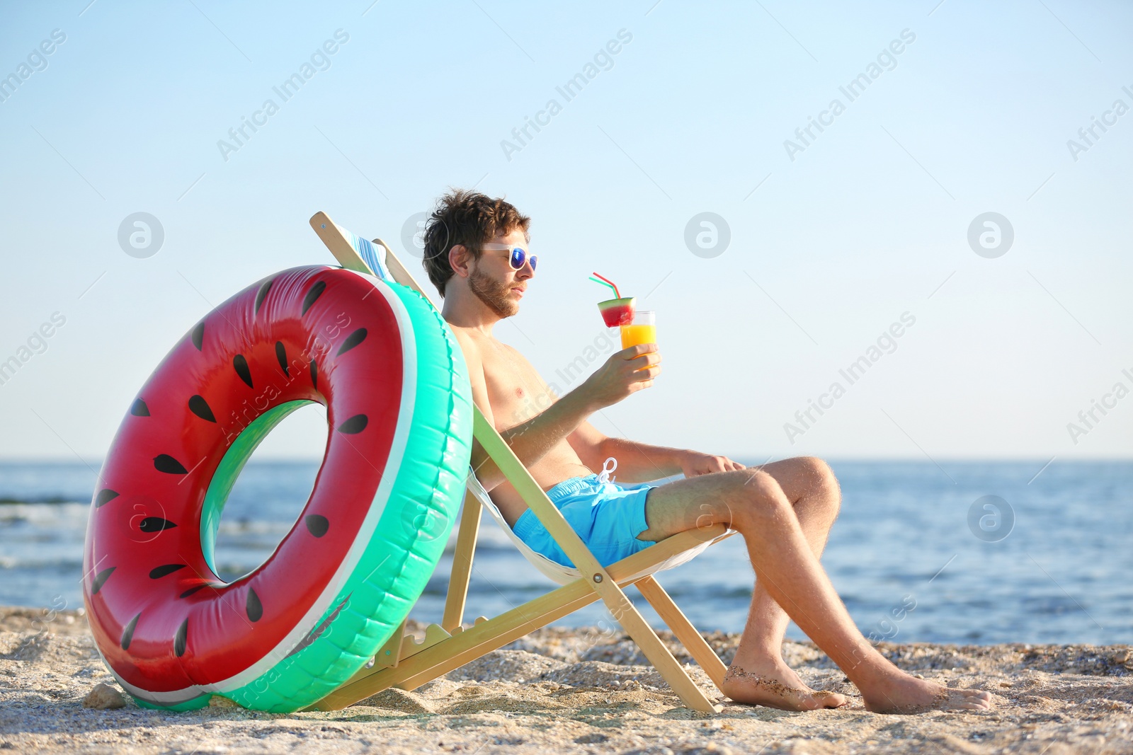 Photo of Young man with cocktail in beach chair at seacoast