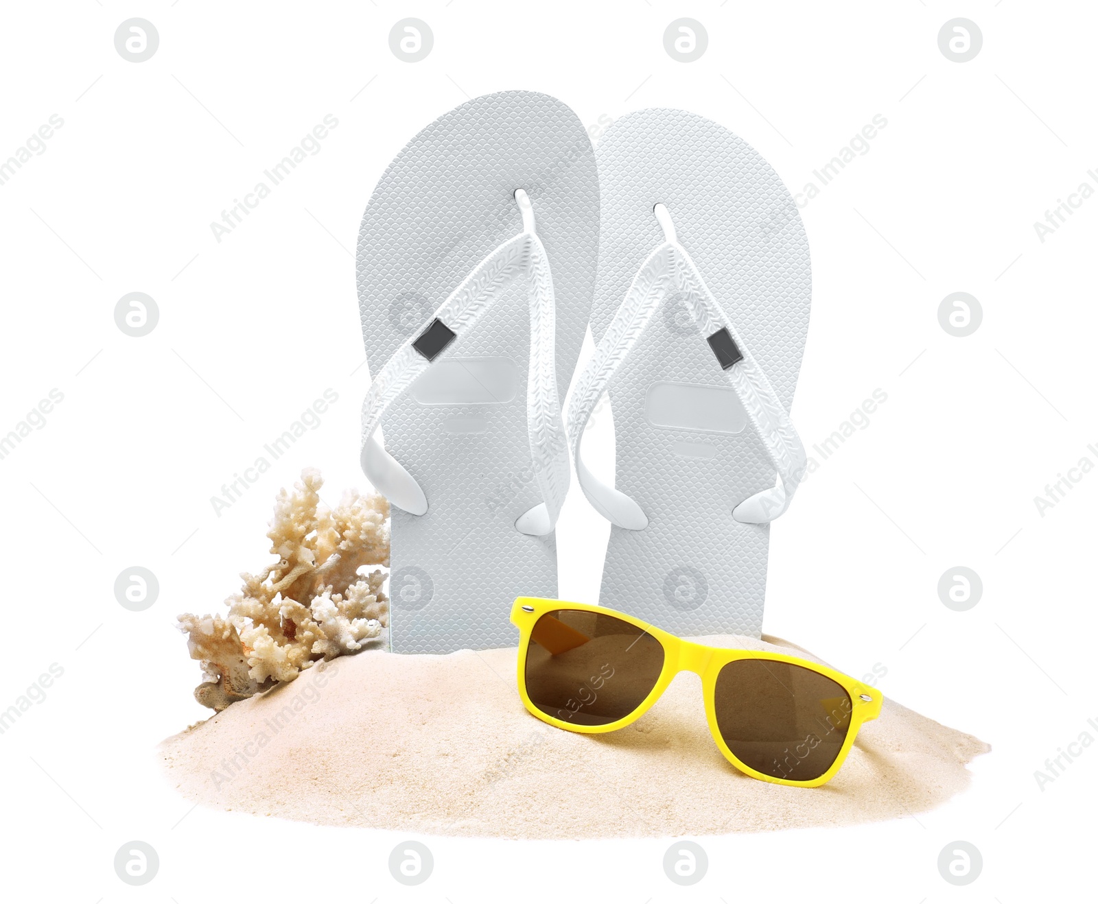 Photo of Bright flip flops in sand, coral and sunglasses on white background