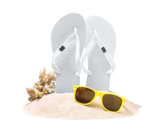 Photo of Bright flip flops in sand, coral and sunglasses on white background
