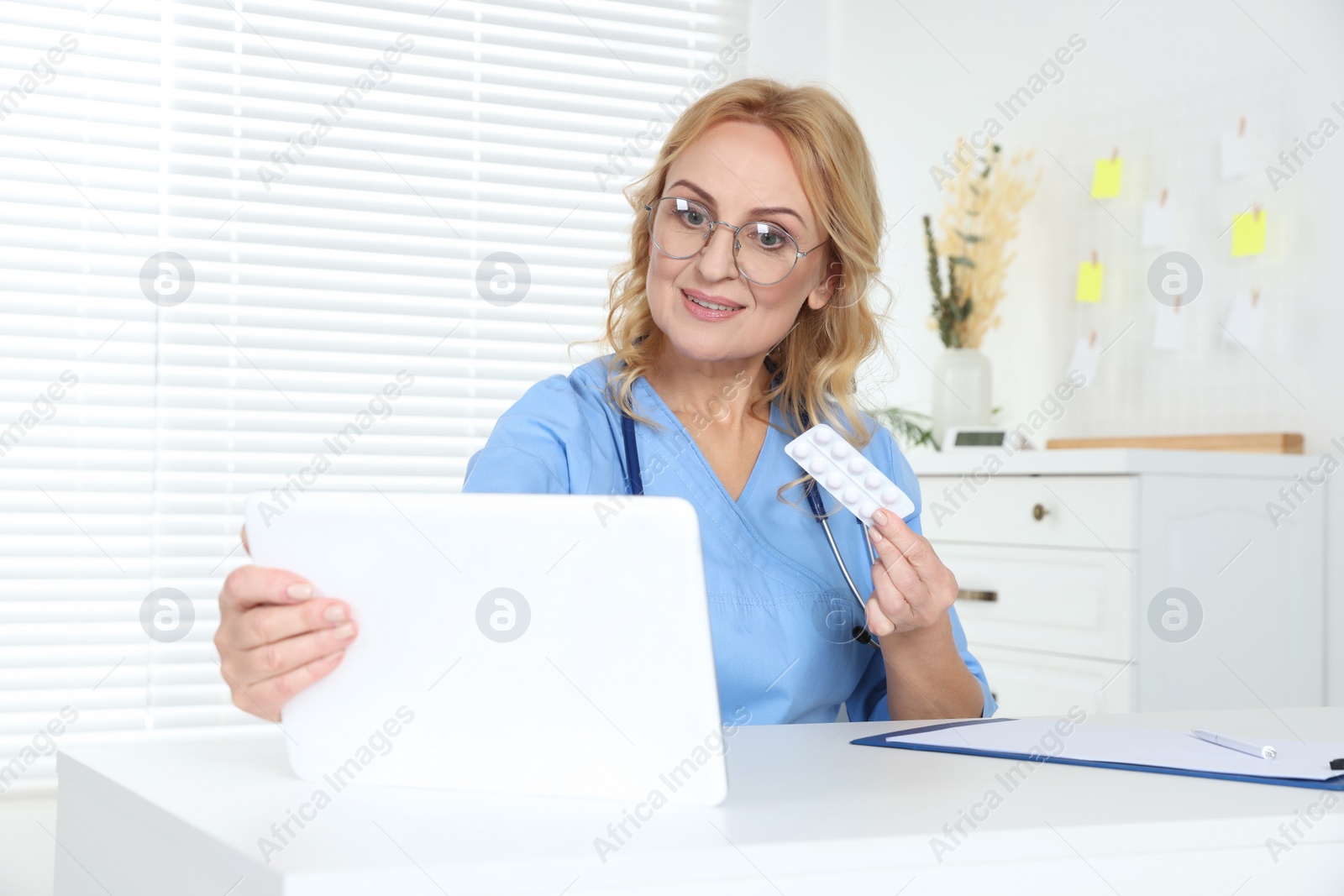 Photo of Doctor with pills and tablet consulting patient in clinic. Online medicine concept