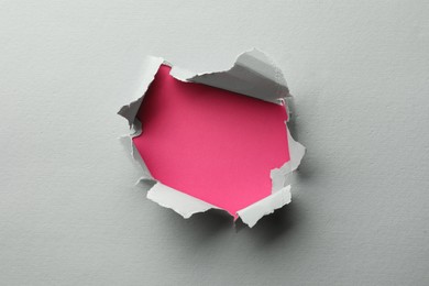 Photo of Hole in white paper on pink background