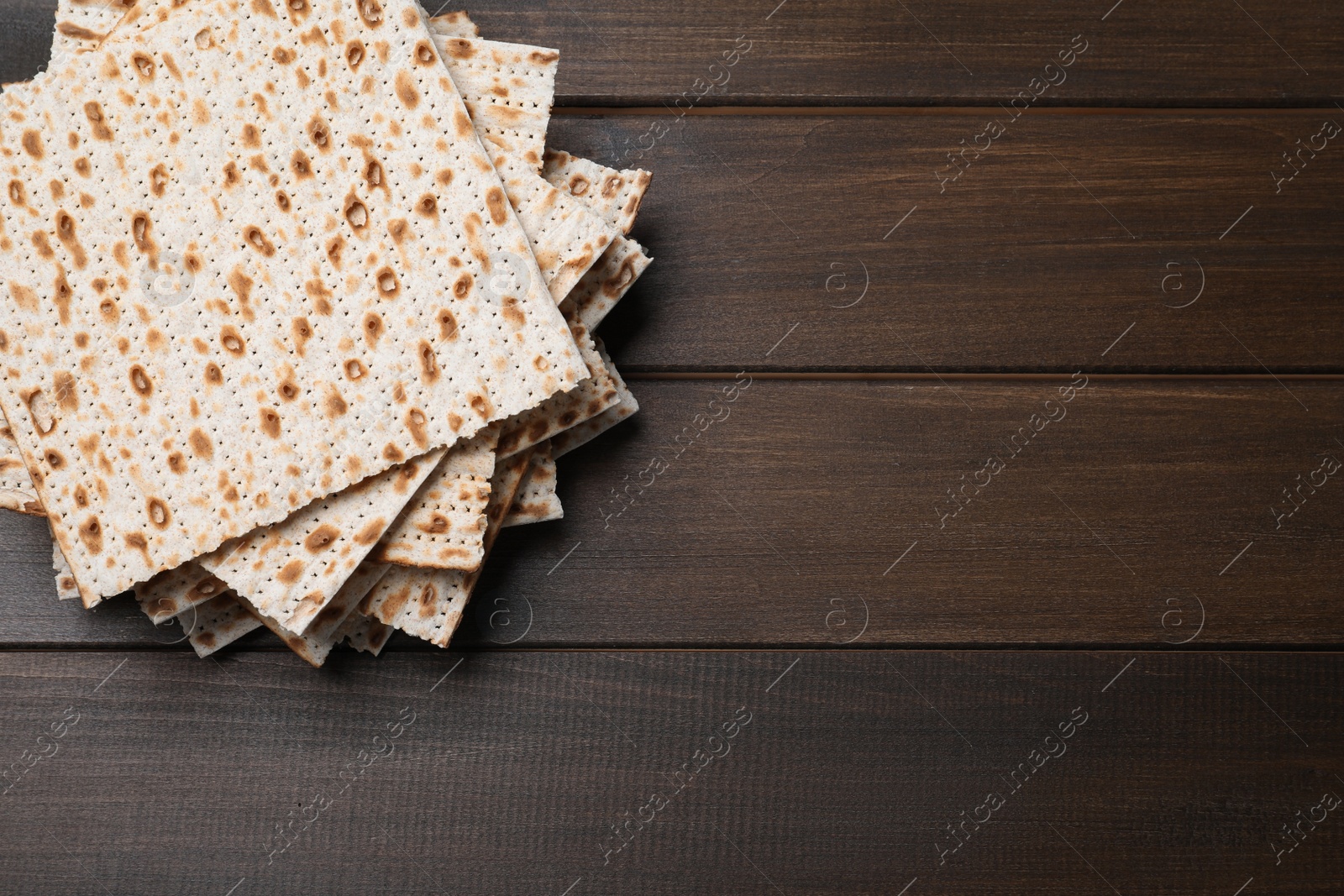 Photo of Stack of matzos on wooden table, top view. Space for text