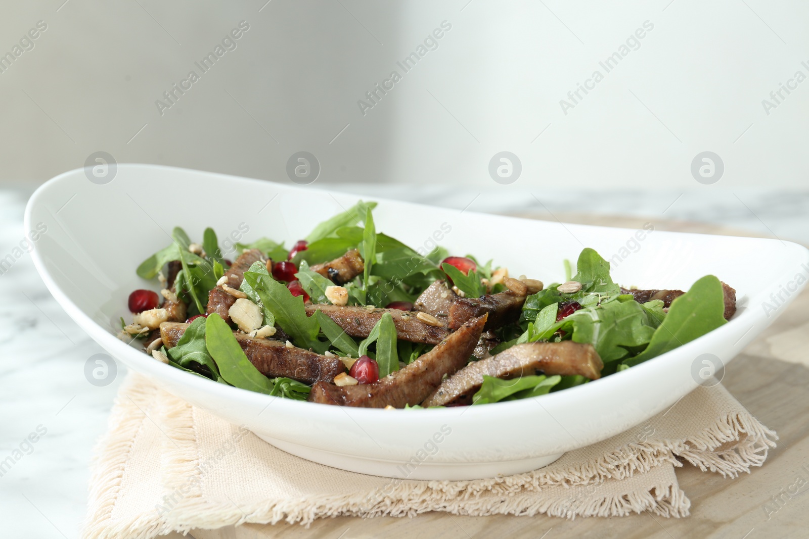 Photo of Delicious salad with beef tongue, arugula and seeds on table, closeup