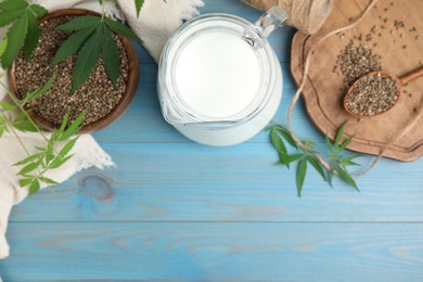 Photo of Hemp milk, seeds and leaves on light blue wooden background, flat lay. Space for text
