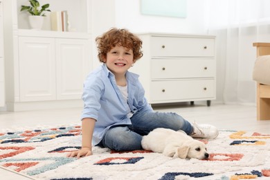 Little boy with cute puppy on carpet at home