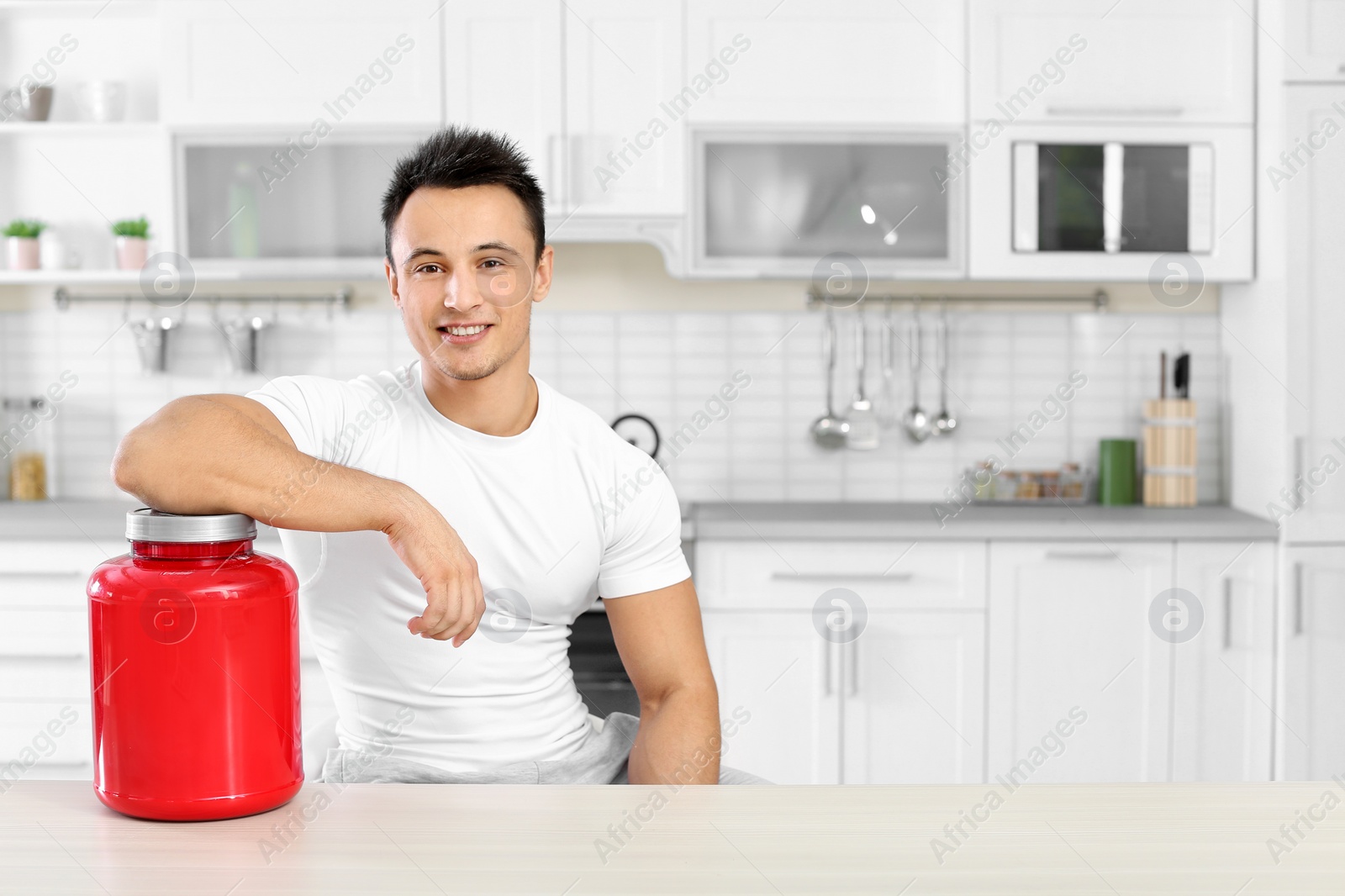 Photo of Man with jar of protein shake powder in kitchen. Space for text
