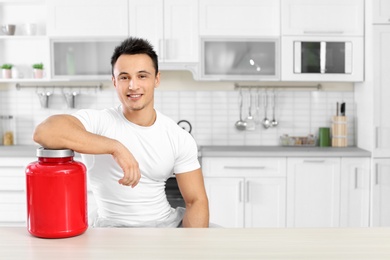 Man with jar of protein shake powder in kitchen. Space for text