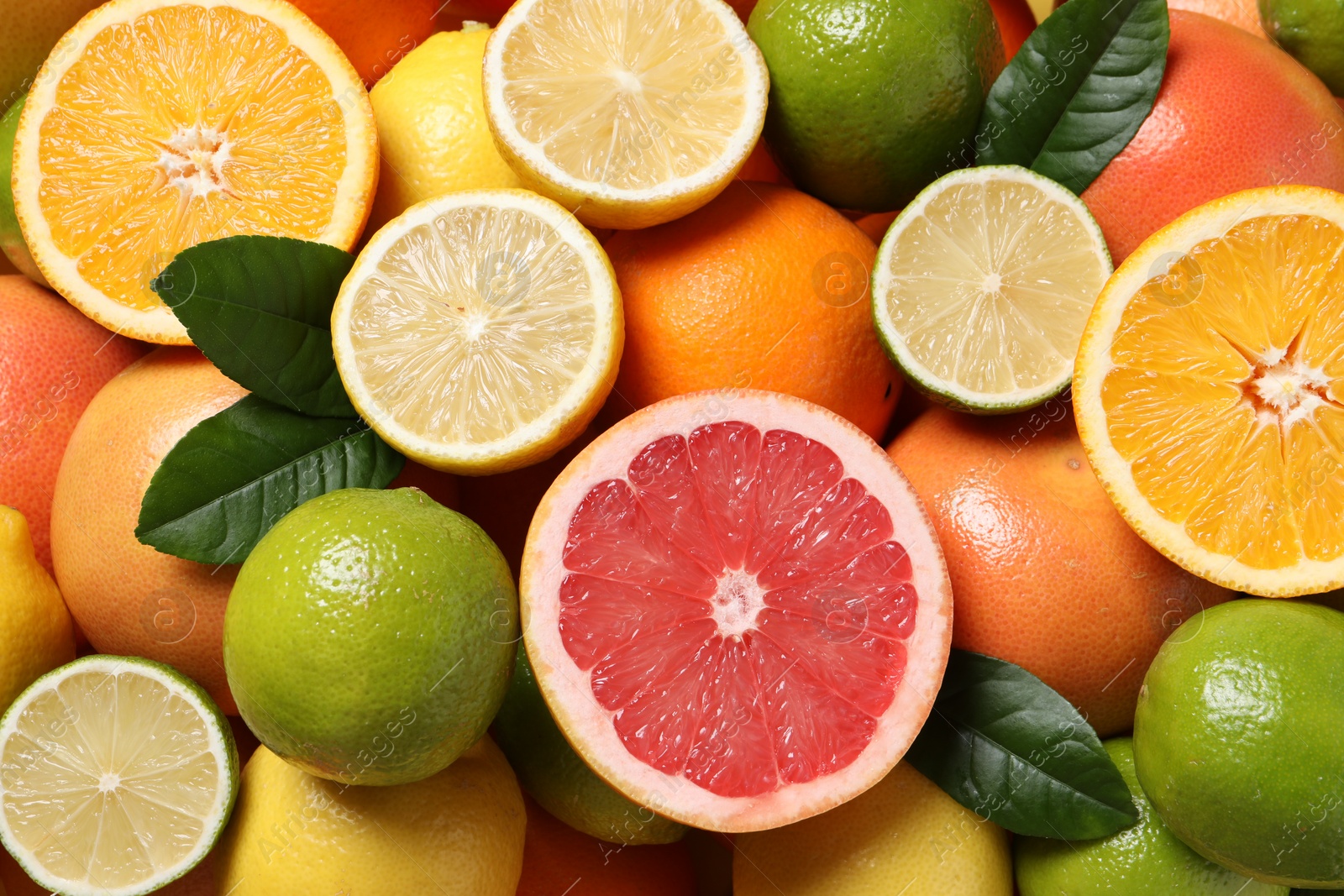 Photo of Different fresh citrus fruits and leaves as background, top view