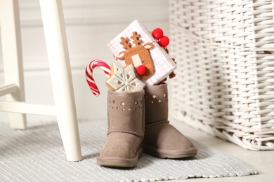 Photo of Sweets and gift box in child's boots indoors. St. Nicholas Day tradition