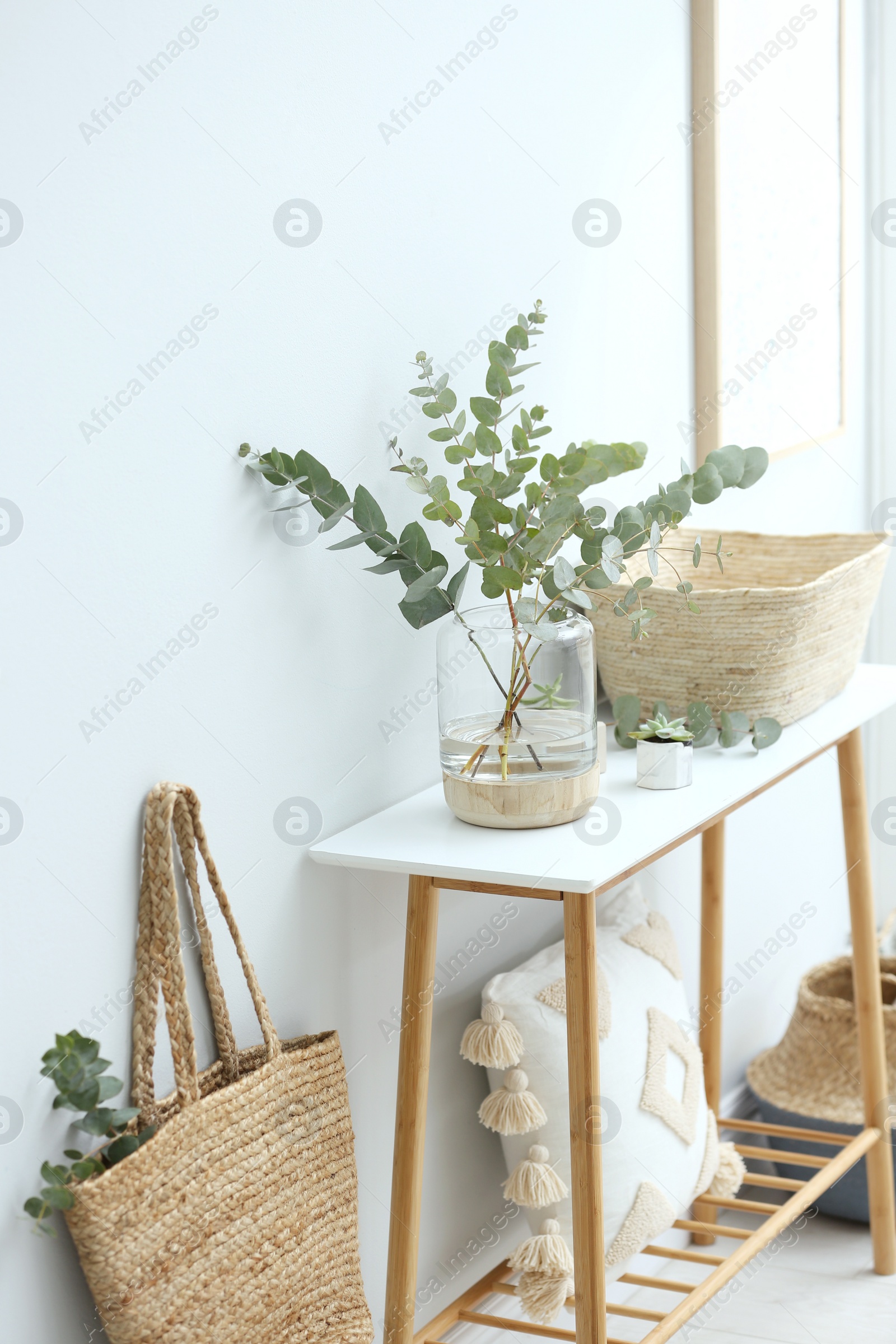 Photo of Vase with fresh eucalyptus branches on table in room. Interior design