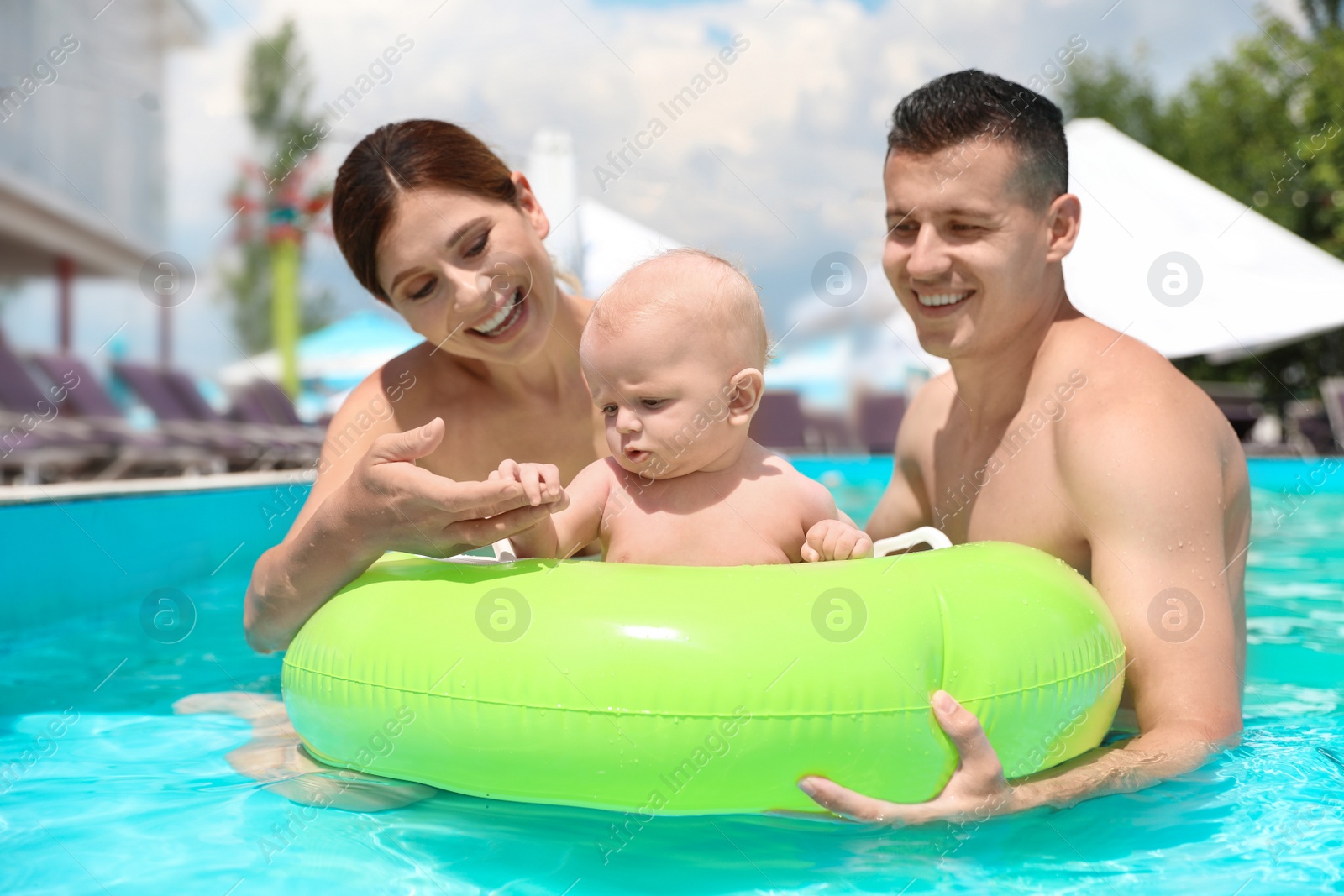 Photo of Happy parents with little baby in swimming pool on sunny day, outdoors