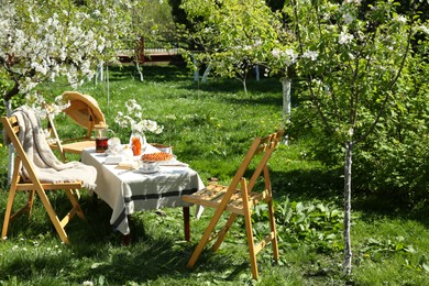 Photo of Beautiful table setting with spring flowers in garden on sunny day