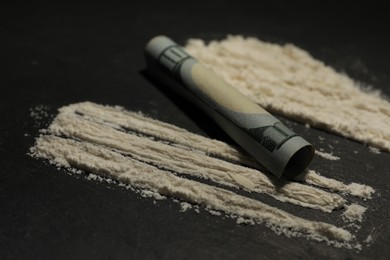 Photo of Drug addiction. Cocaine and rolled dollar banknote on grey textured table, closeup