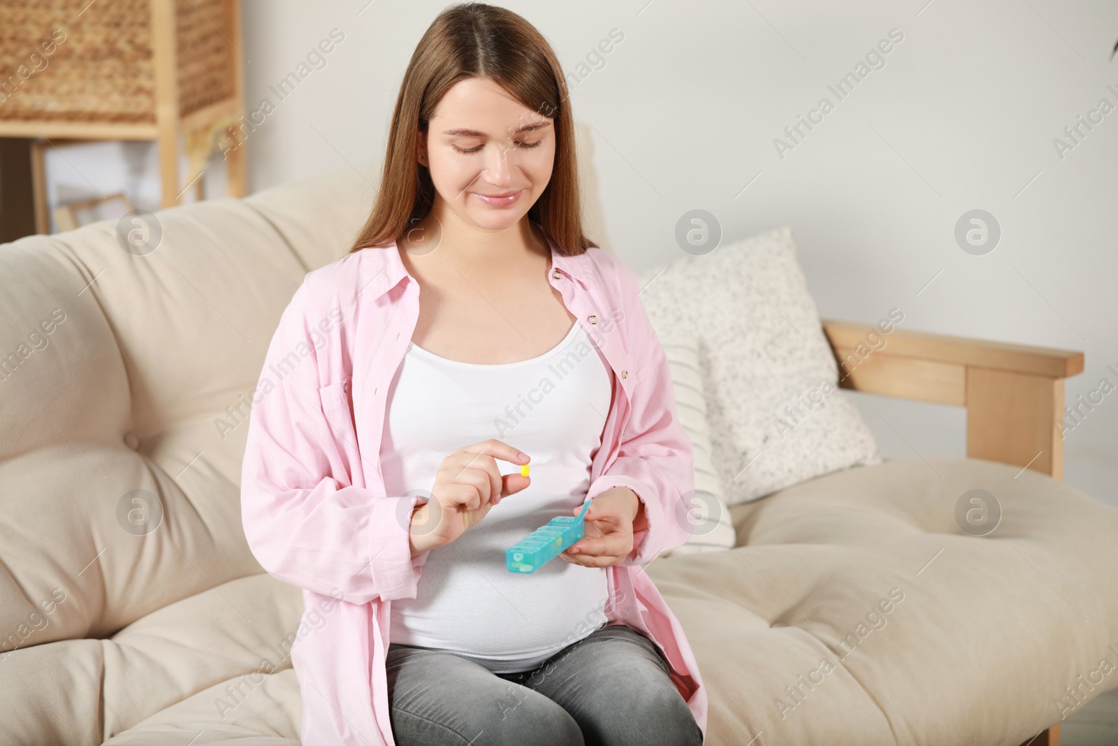 Photo of Beautiful pregnant woman holding pill at home