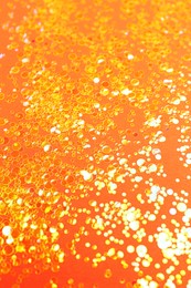 Photo of Shiny bright golden glitter on orange background