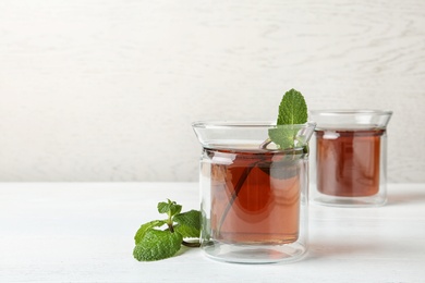 Glass cups with tasty tea on white table. Space for text