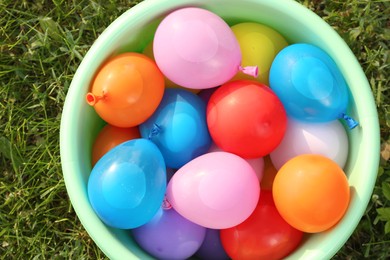 Basin full of water bombs on green grass, top view