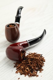 Smoking pipes with tobacco on white wooden table