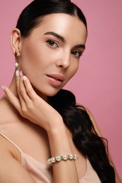 Photo of Young woman wearing elegant pearl jewelry on pink background
