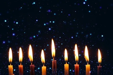 Hanukkah celebration. Burning candles on dark background, closeup