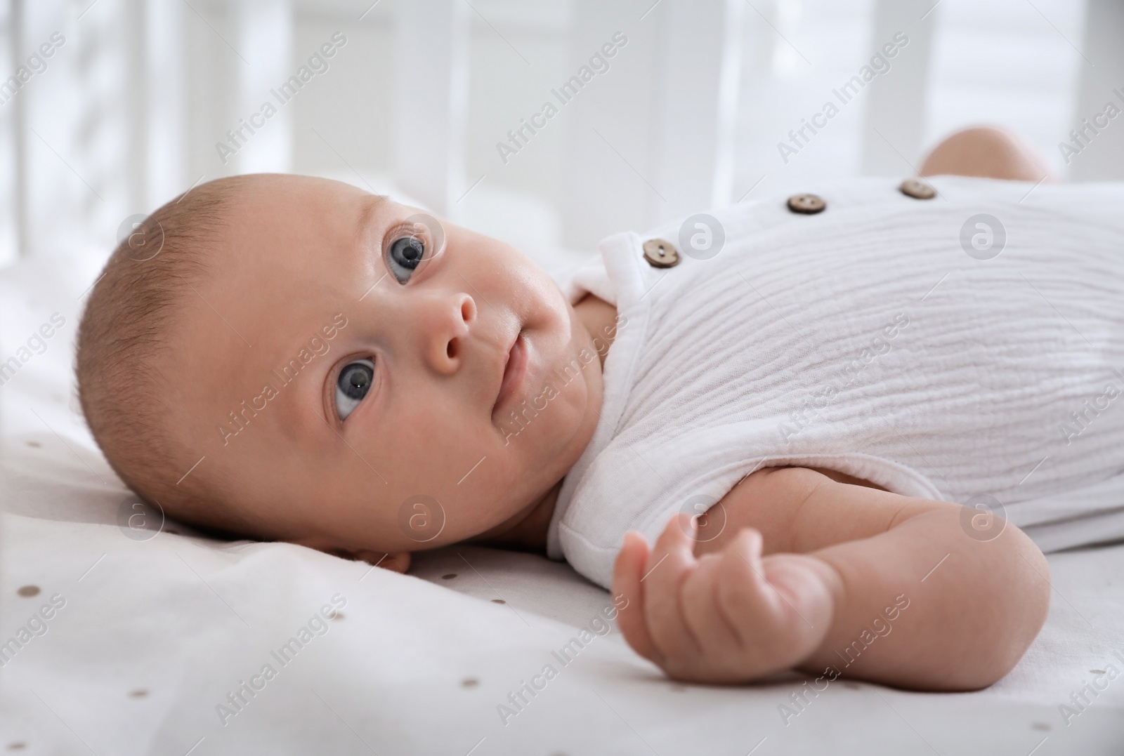 Photo of Cute little baby lying on bed at home, closeup