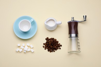 Photo of Flat lay composition with manual coffee grinder and beans on beige background