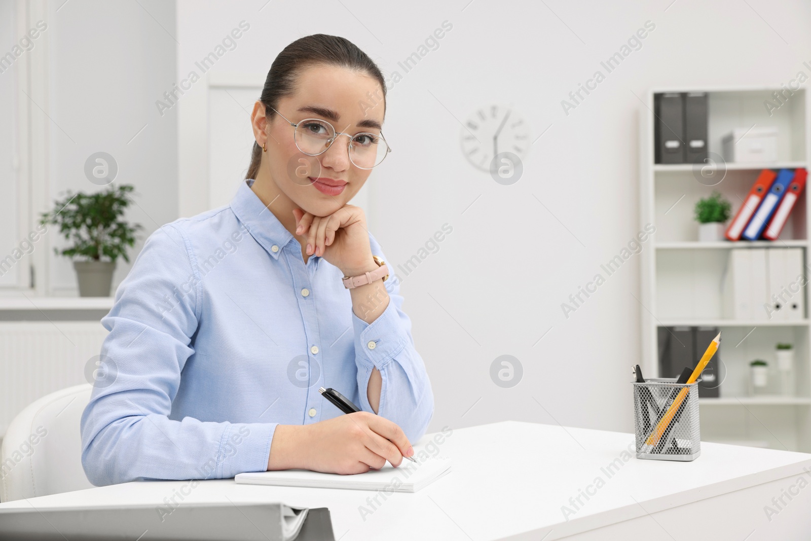 Photo of Young female intern working at table in office