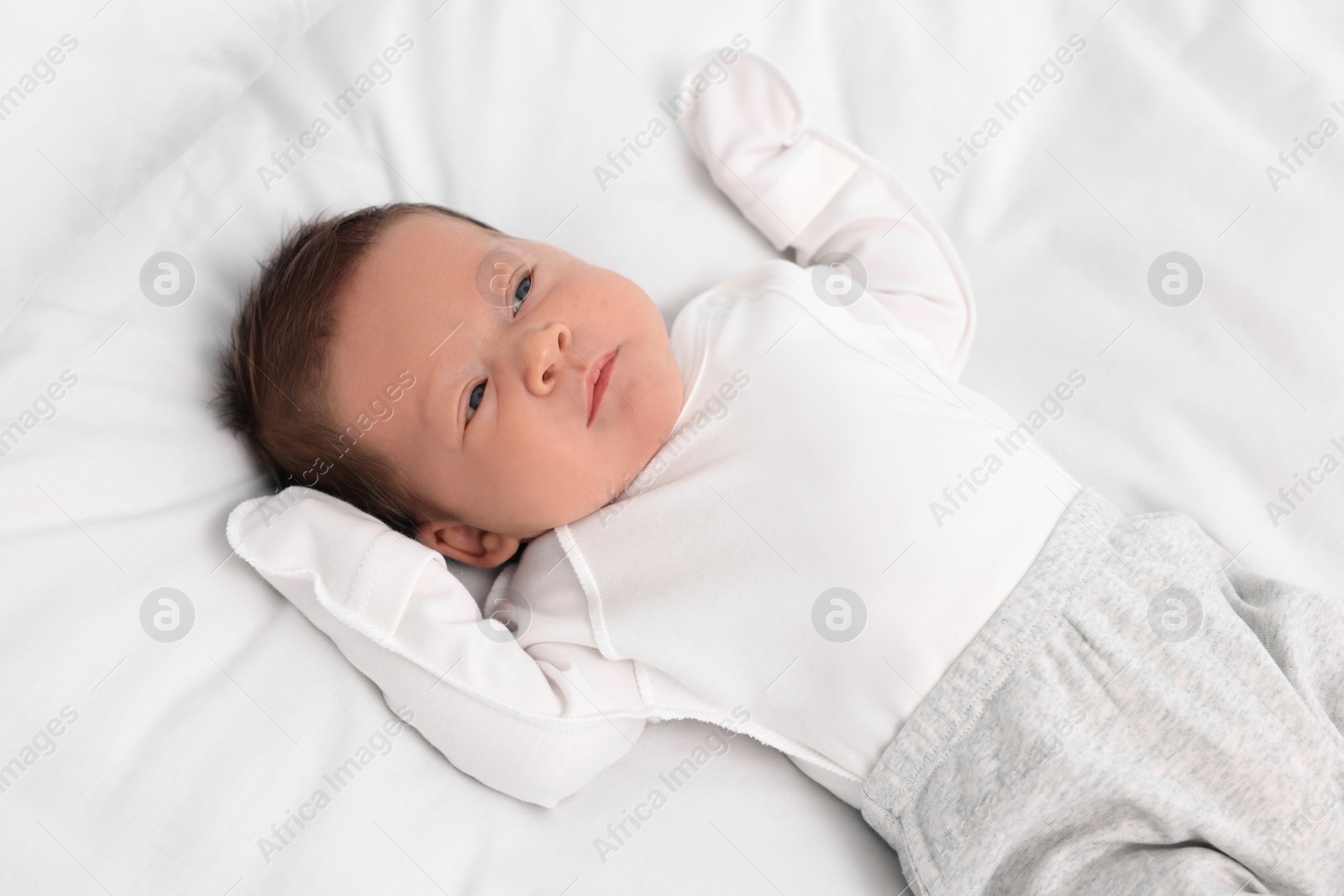 Photo of Cute newborn baby lying on white soft bed