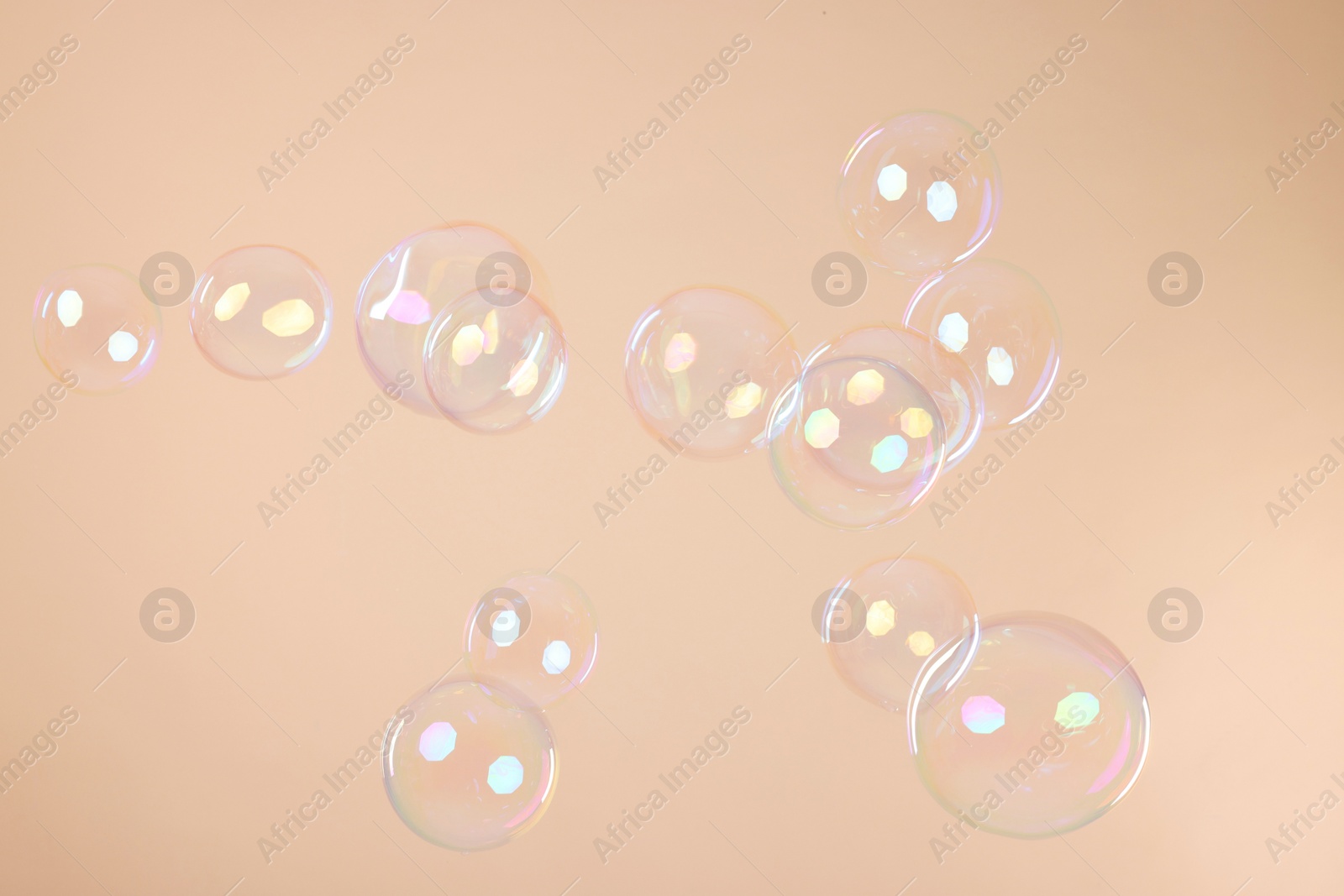 Photo of Many beautiful soap bubbles on beige background