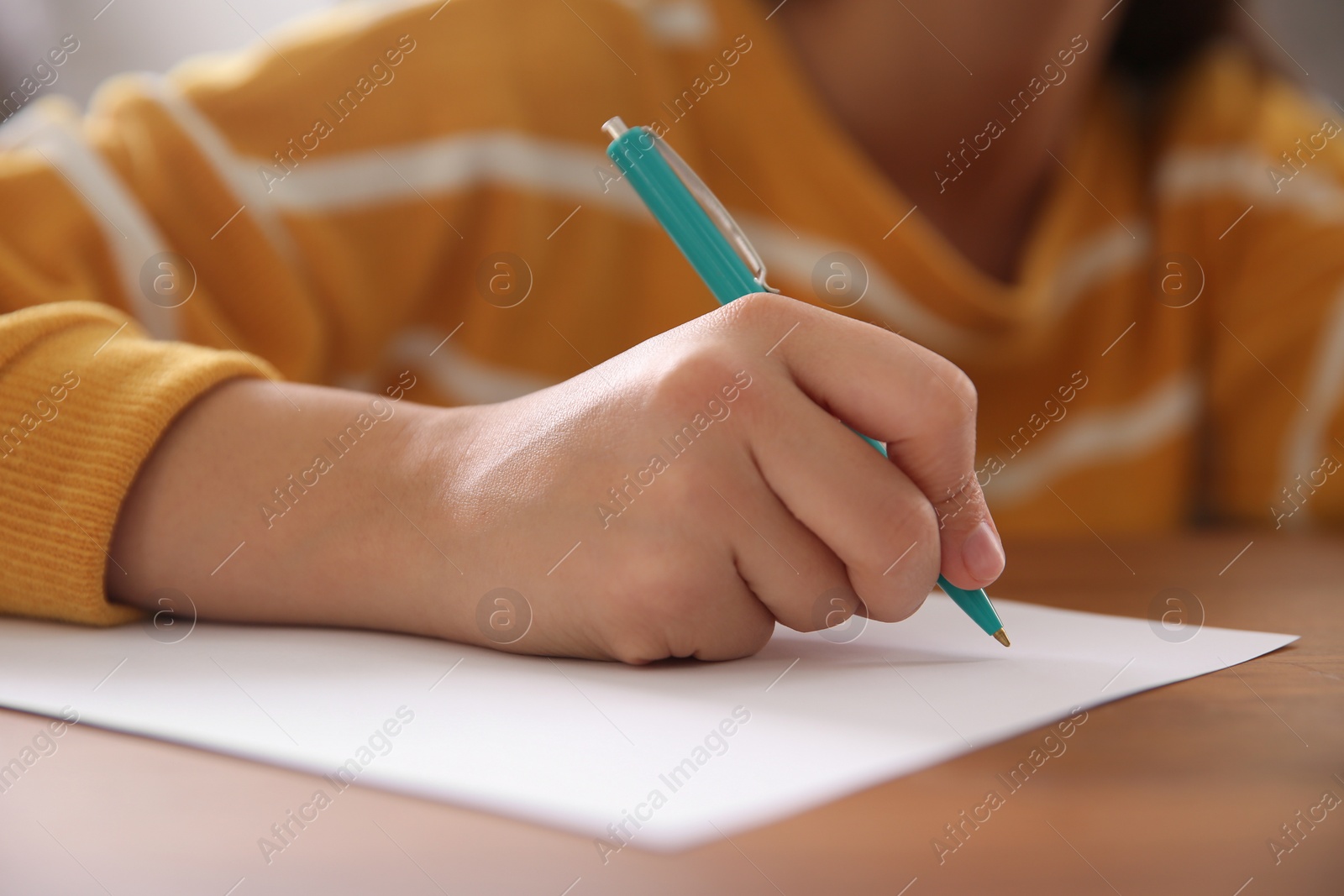 Photo of Woman writing letter at wooden table indoors, closeup