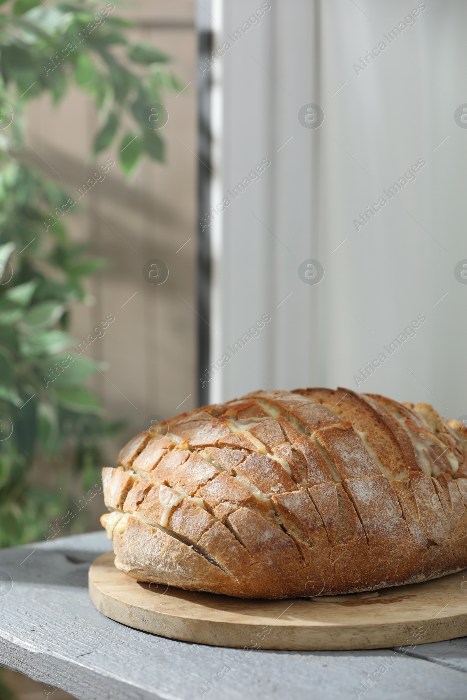 Photo of Freshly baked bread with tofu cheese on grey wooden table indoors