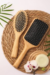 Wooden hairbrushes, solid shampoo, orchid flowers and leaves on white background, flat lay