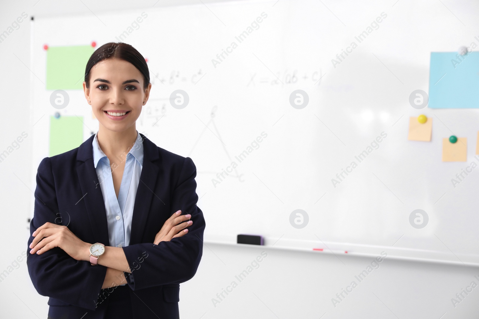 Photo of Young teacher near whiteboard in modern classroom. Space for text