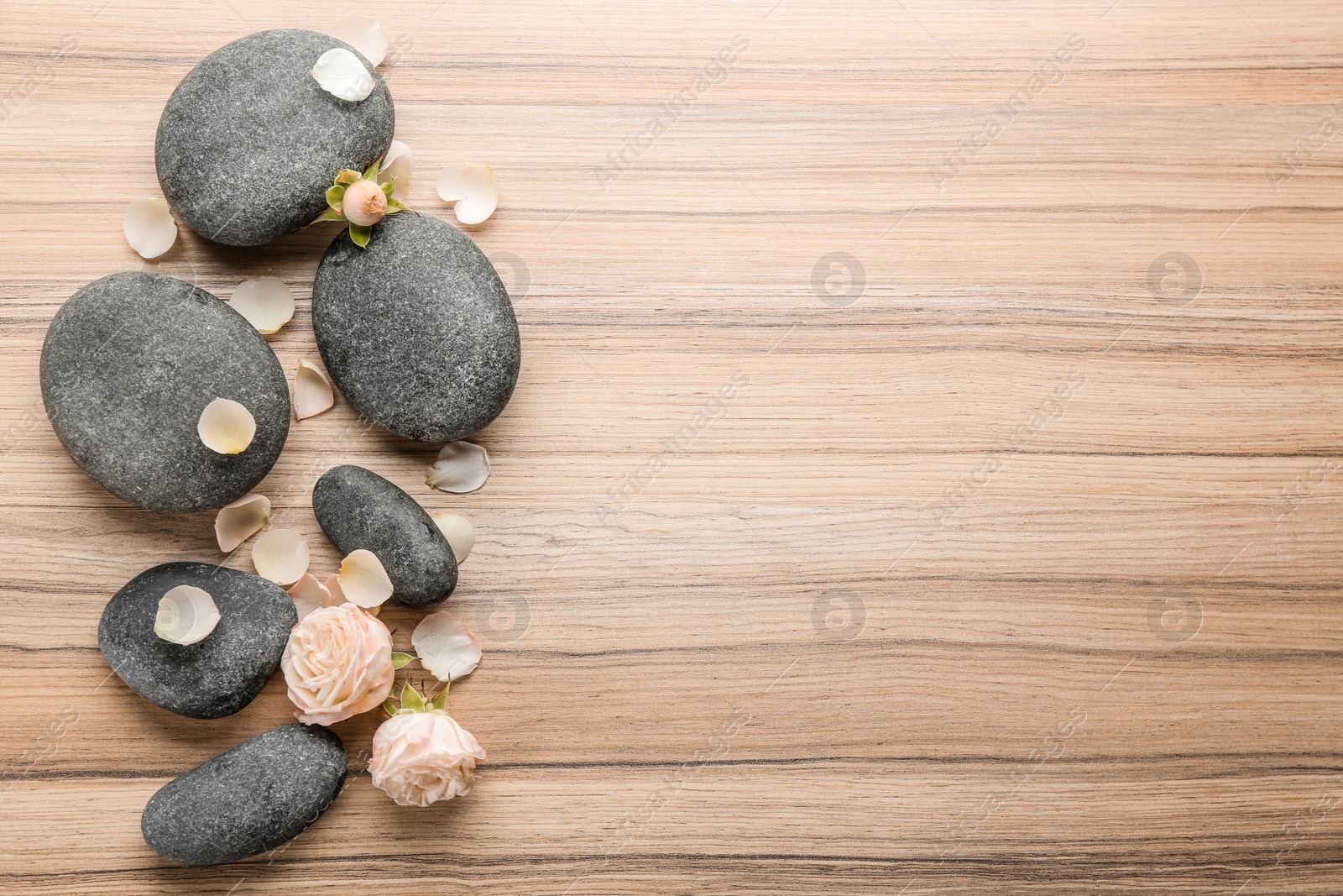 Photo of Stones and rose flowers on wooden background, top view with space for text. Zen lifestyle