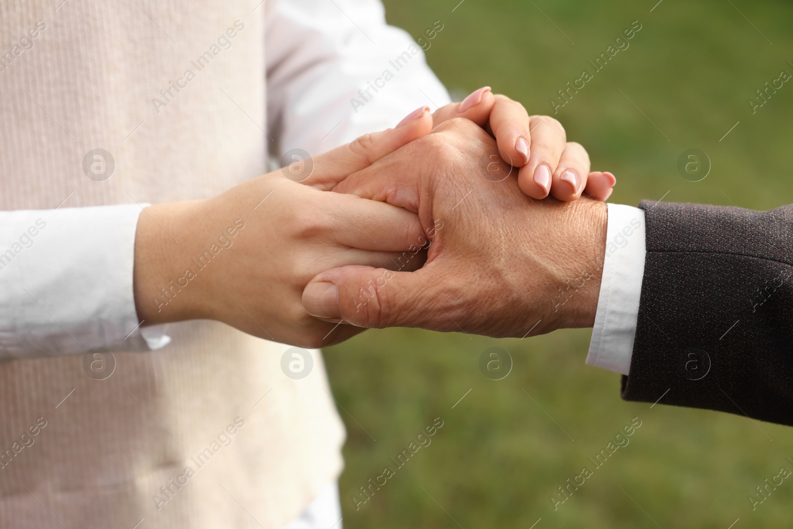 Photo of Trust and deal. Partners joining hands outdoors, closeup
