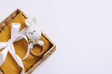 Baby accessory. Rattle and child`s clothes in wicker box on white background, top view. Space for text