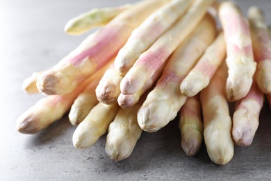 Pile of fresh white asparagus on grey table, closeup