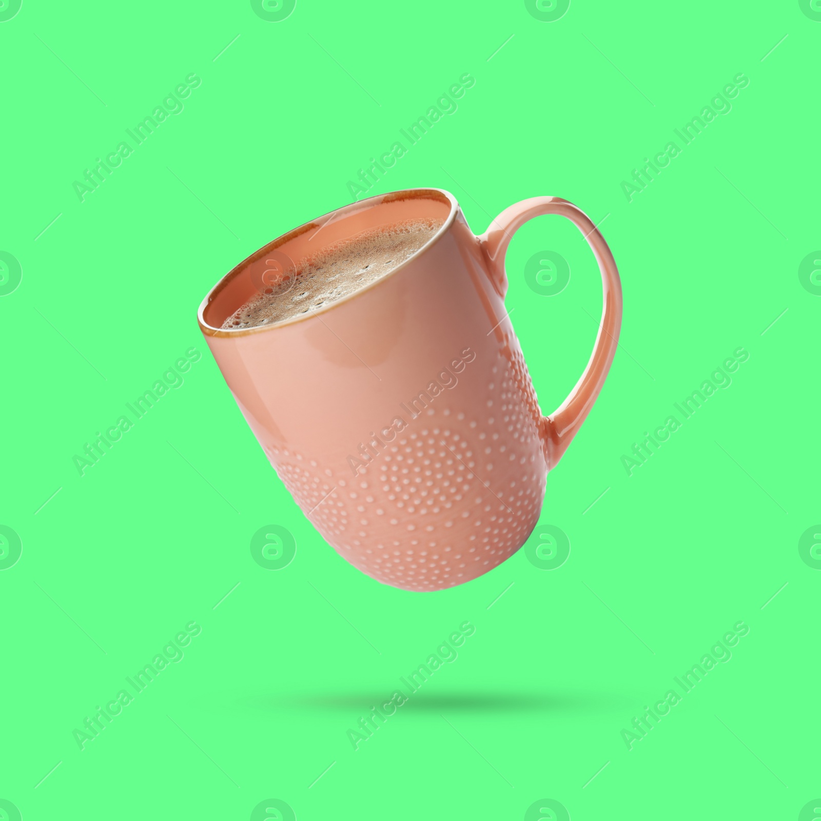 Image of Beige cup of coffee drink levitating on green background