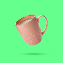 Beige cup of coffee drink levitating on green background
