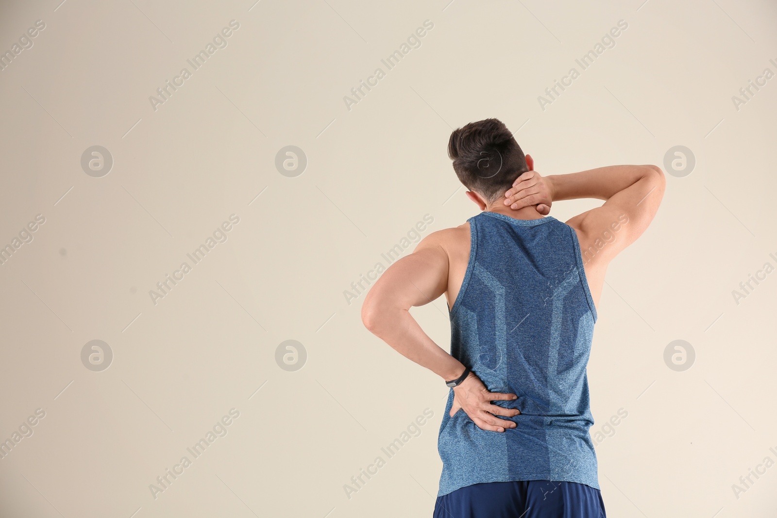 Photo of Man in sportswear suffering from back pain on light background