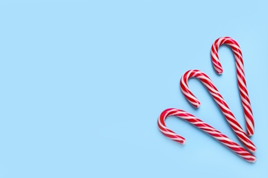 Sweet Christmas candy canes on light blue background, flat lay. Space for text